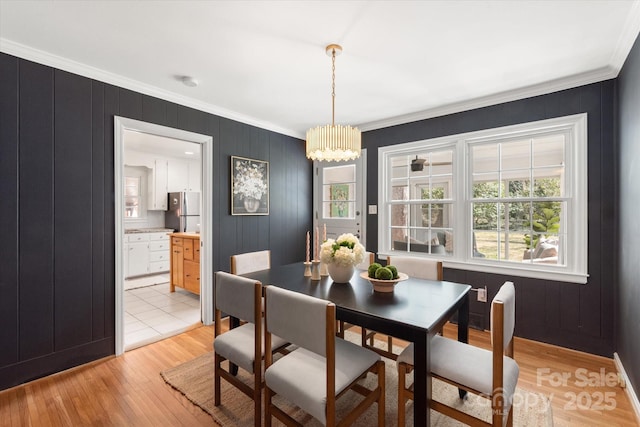 dining area with a chandelier, light wood-type flooring, and crown molding