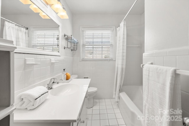 full bath with vanity, tile patterned flooring, wainscoting, tile walls, and toilet