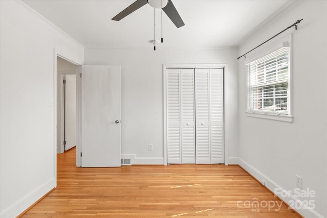 unfurnished bedroom with light wood-style flooring, baseboards, a closet, and ornamental molding