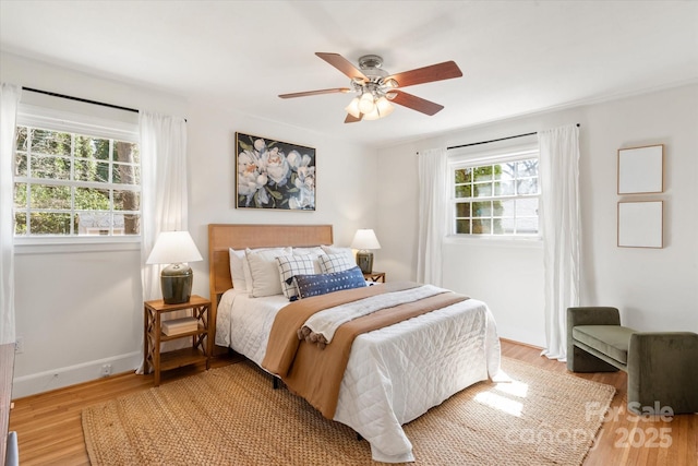 bedroom with baseboards, light wood-style flooring, and a ceiling fan