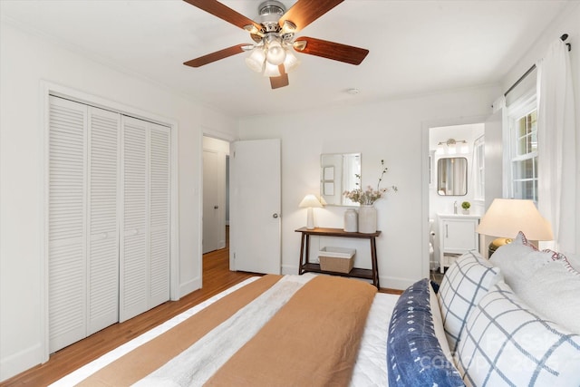 bedroom with wood finished floors, a closet, ensuite bathroom, and baseboards