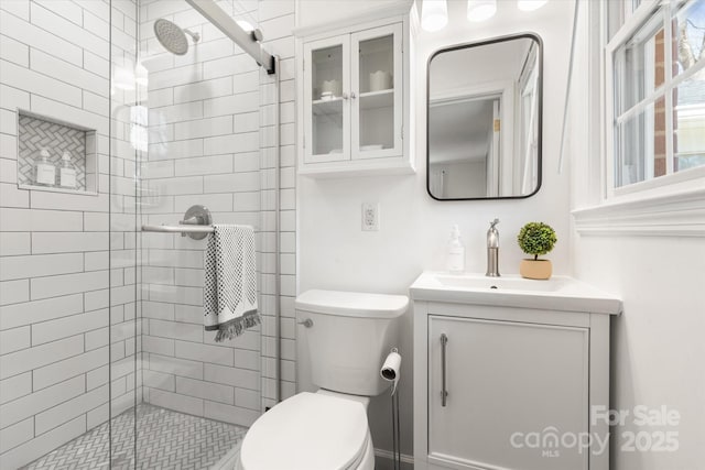 full bathroom featuring a stall shower, toilet, and vanity