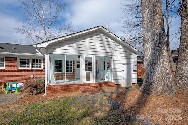 view of front of home with brick siding and roof with shingles