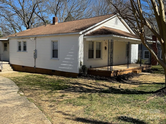 exterior space with crawl space, a chimney, and a lawn