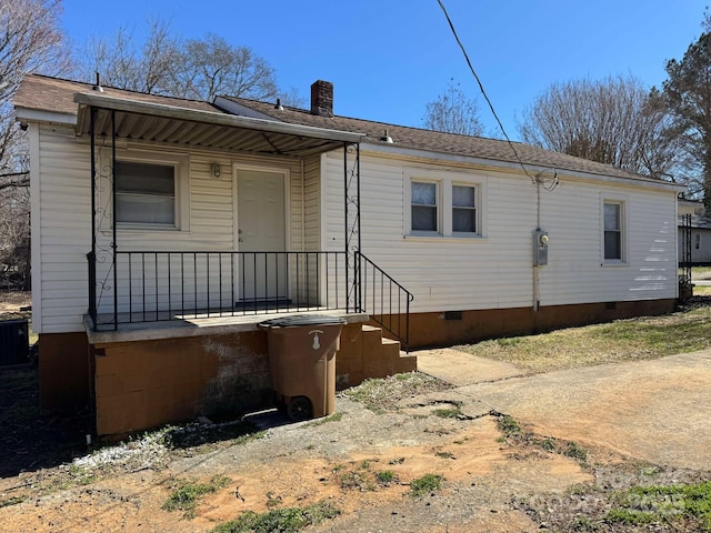 back of property with crawl space and a chimney