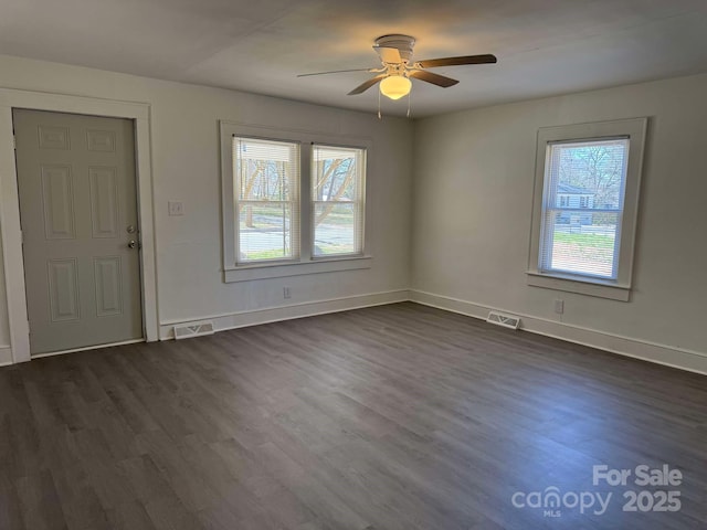 interior space with plenty of natural light, dark wood finished floors, visible vents, and baseboards