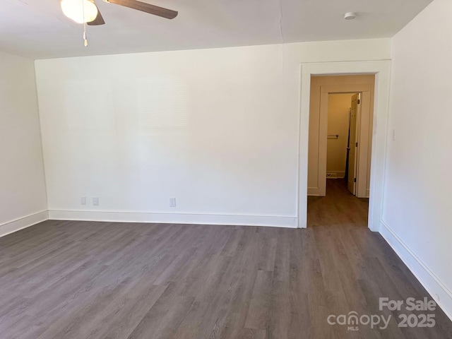 empty room featuring dark wood-style flooring, a ceiling fan, and baseboards