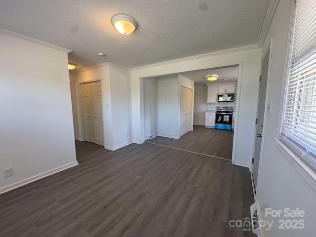 empty room with dark wood-style floors, crown molding, a textured ceiling, and baseboards