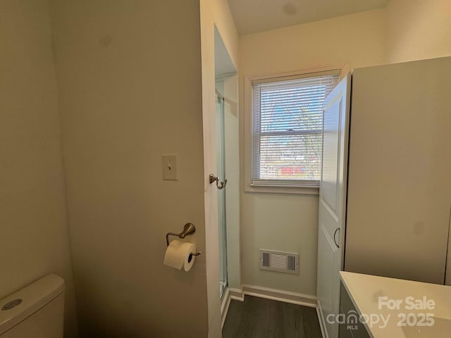 bathroom with toilet, wood finished floors, visible vents, baseboards, and a shower stall