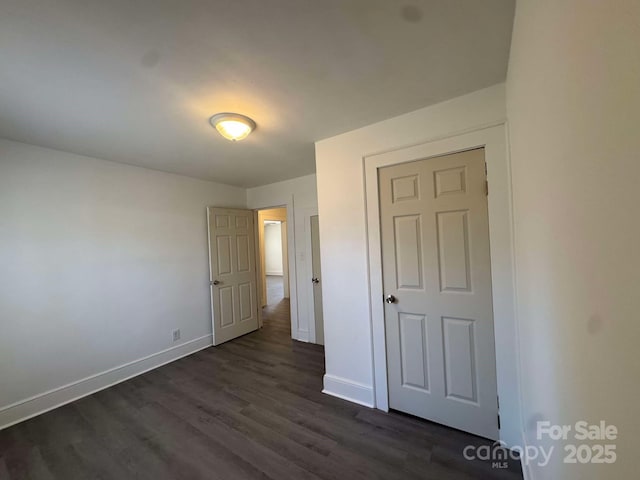 unfurnished bedroom featuring dark wood-type flooring and baseboards