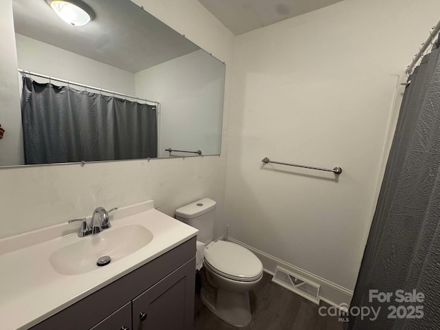 bathroom with visible vents, toilet, vanity, wood finished floors, and baseboards