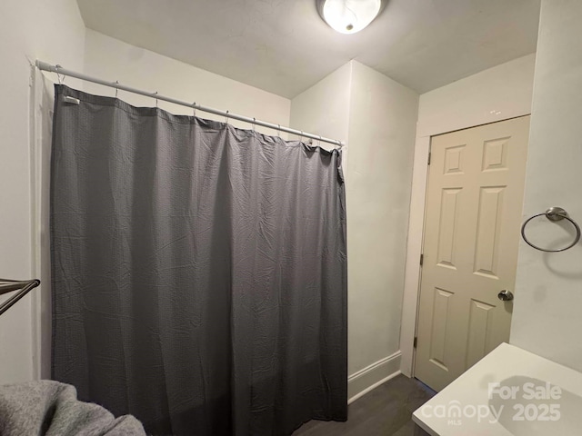 full bathroom with a shower with shower curtain and wood finished floors