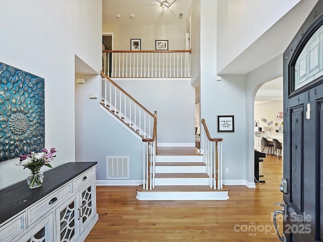 entrance foyer with arched walkways, visible vents, stairway, and light wood finished floors