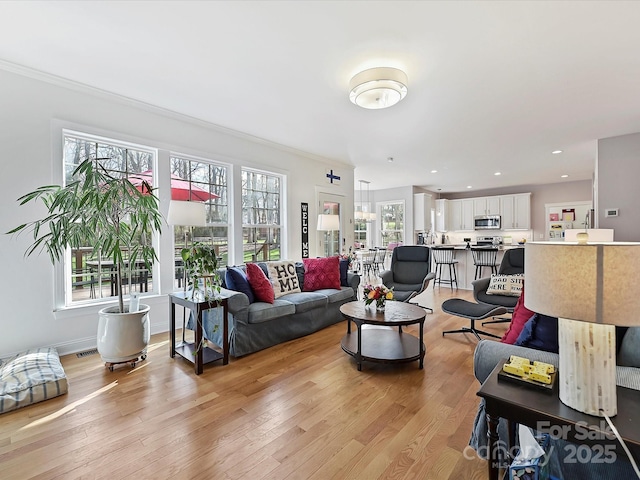 living area with recessed lighting, crown molding, light wood-style flooring, and baseboards