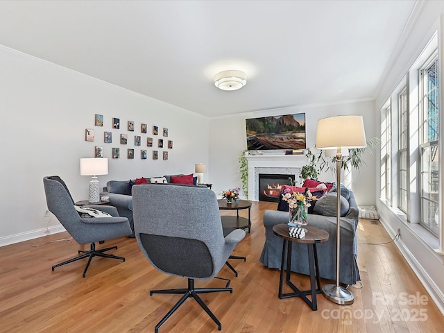 living area featuring crown molding, baseboards, wood finished floors, and a glass covered fireplace