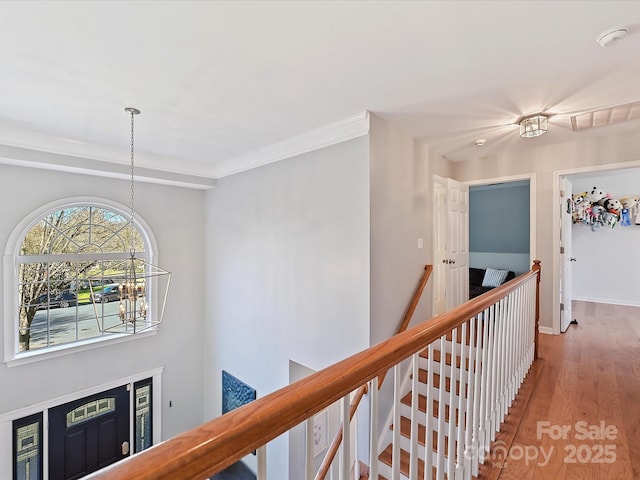 hallway with a chandelier, wood finished floors, visible vents, an upstairs landing, and baseboards