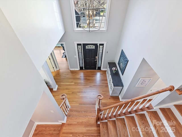 entryway with stairs, wood finished floors, a towering ceiling, and a wealth of natural light