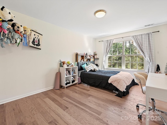 bedroom featuring wood finished floors, visible vents, and baseboards