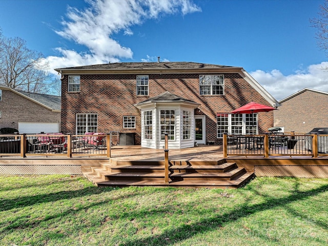 back of house featuring a deck, brick siding, and a lawn