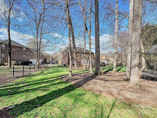 view of yard featuring a trampoline and fence