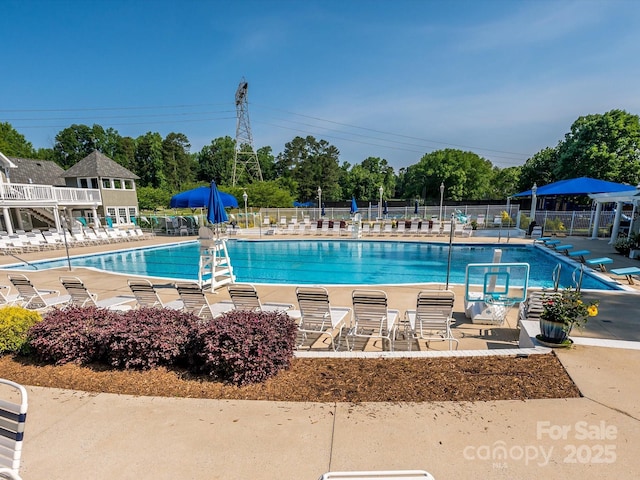 community pool with a patio area and fence