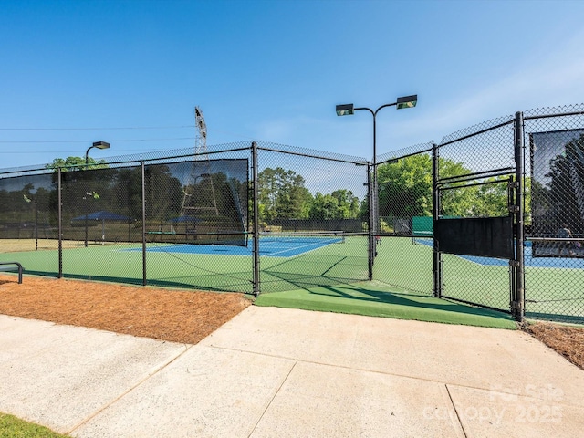 view of tennis court with a gate and fence