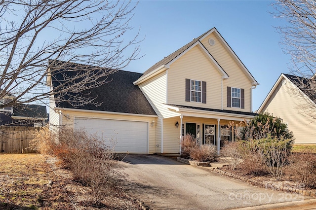 traditional home featuring aphalt driveway, fence, an attached garage, and a shingled roof