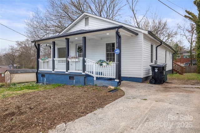 shotgun-style home with a porch, crawl space, an outdoor structure, and a shed
