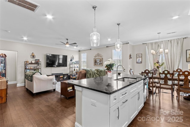 kitchen featuring an island with sink, dark wood-style floors, visible vents, and a sink