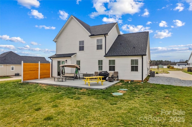 rear view of property with a patio, central AC, fence, a yard, and a shingled roof