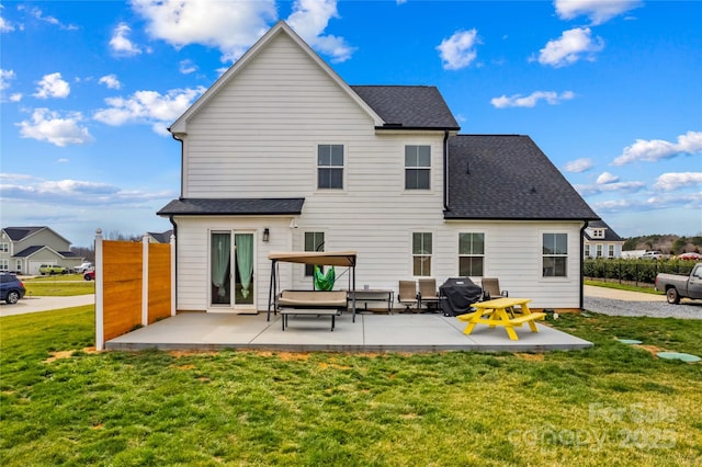 rear view of property with a lawn, a shingled roof, and a patio