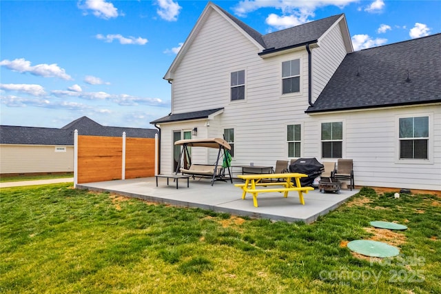 rear view of house featuring a fire pit, a shingled roof, fence, a yard, and a patio area