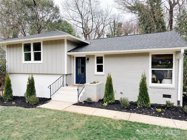 split level home with crawl space, roof with shingles, a front lawn, and brick siding