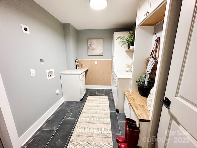 clothes washing area featuring hookup for an electric dryer, dark tile patterned floors, washer hookup, baseboards, and cabinet space