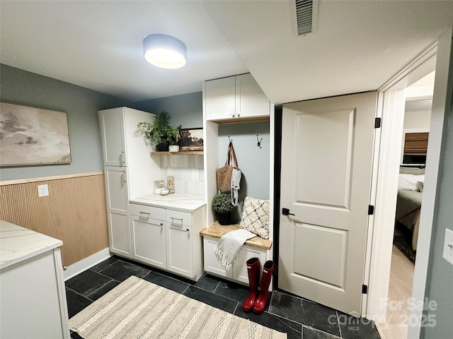 mudroom featuring wooden walls, visible vents, and wainscoting