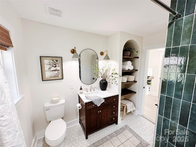 bathroom with built in shelves, visible vents, toilet, a tile shower, and vanity