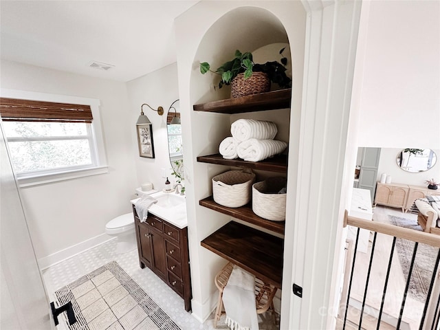 bathroom featuring toilet, baseboards, visible vents, and vanity