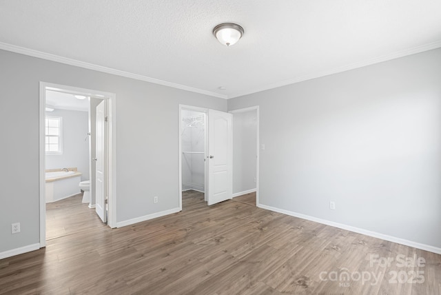 6 Clark Meadow Ln, Candler, NC 28715 - unfurnished bedroom featuring baseboards, ornamental molding, wood finished floors, and a spacious closet