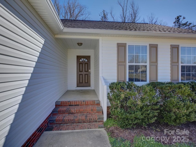 doorway to property featuring a shingled roof