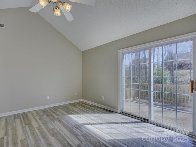 empty room featuring lofted ceiling, visible vents, ceiling fan, wood finished floors, and baseboards