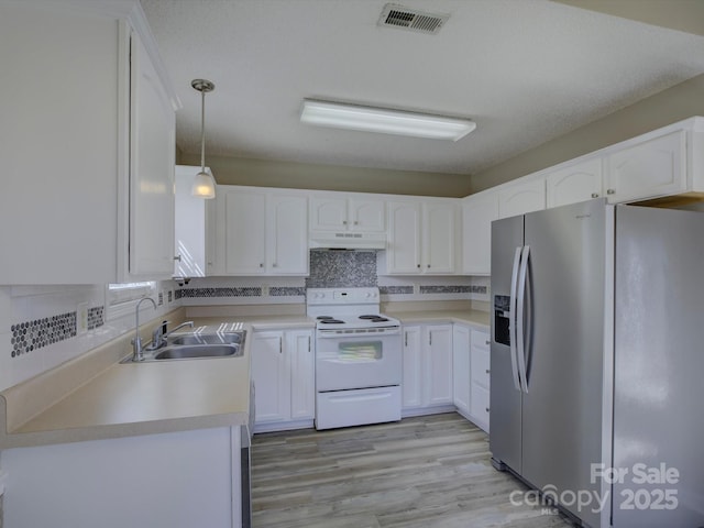 kitchen with under cabinet range hood, white electric range, a sink, visible vents, and stainless steel fridge