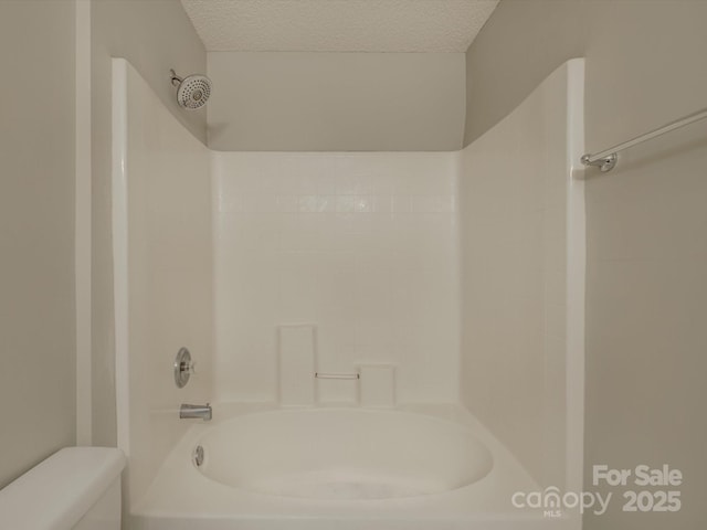 bathroom featuring a textured ceiling, shower / bath combination, and toilet