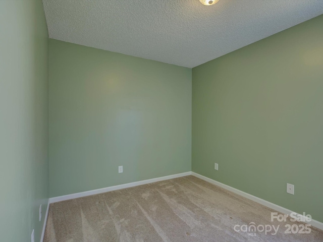 carpeted empty room featuring baseboards and a textured ceiling