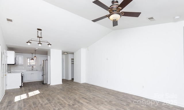 unfurnished living room featuring baseboards, visible vents, lofted ceiling, wood finished floors, and a sink