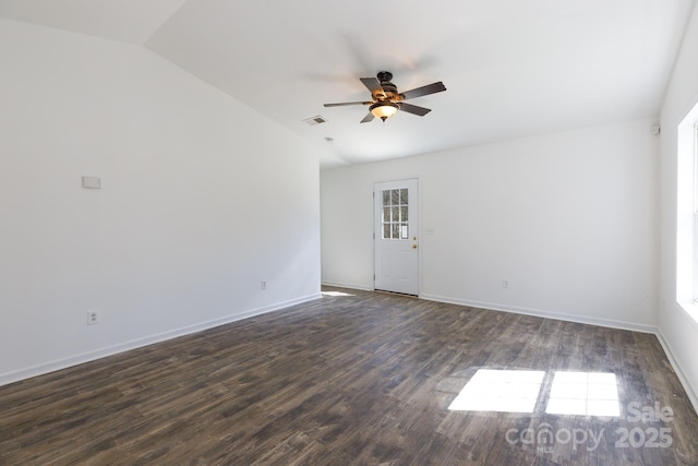 spare room with visible vents, a ceiling fan, vaulted ceiling, wood finished floors, and baseboards