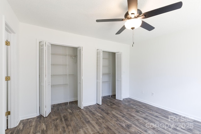 unfurnished bedroom with baseboards, a ceiling fan, wood finished floors, a textured ceiling, and multiple closets