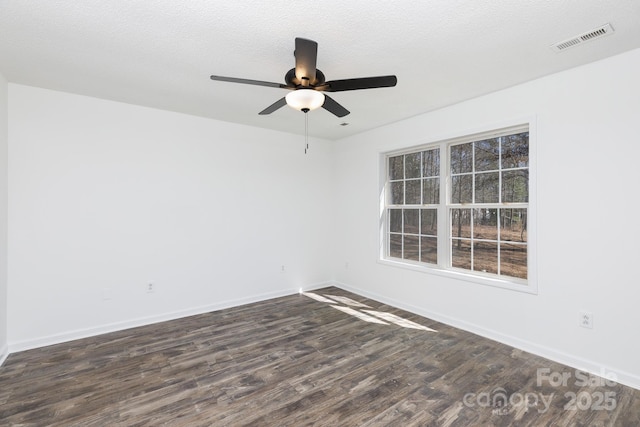 spare room with baseboards, visible vents, a ceiling fan, dark wood finished floors, and a textured ceiling