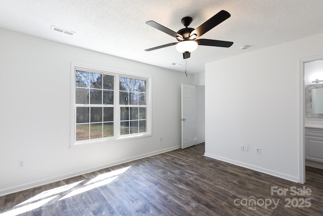 unfurnished bedroom with baseboards, visible vents, dark wood-style floors, ceiling fan, and a textured ceiling