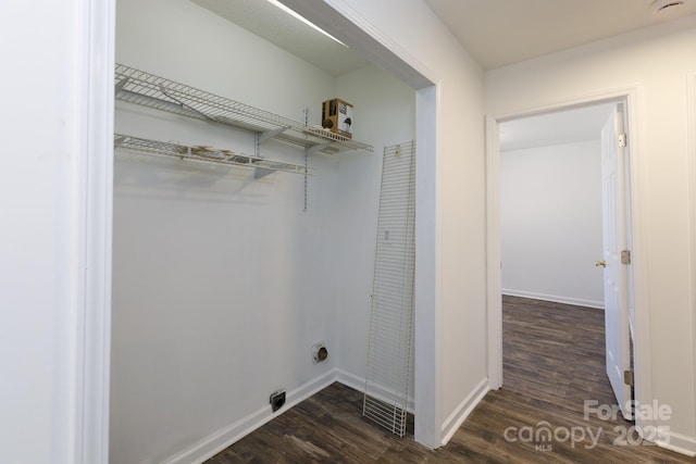 laundry area with laundry area, hookup for an electric dryer, dark wood finished floors, and baseboards