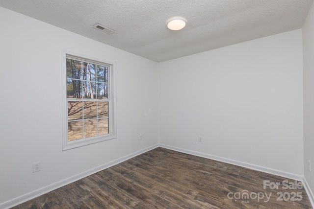 empty room featuring baseboards, a textured ceiling, visible vents, and dark wood-style flooring